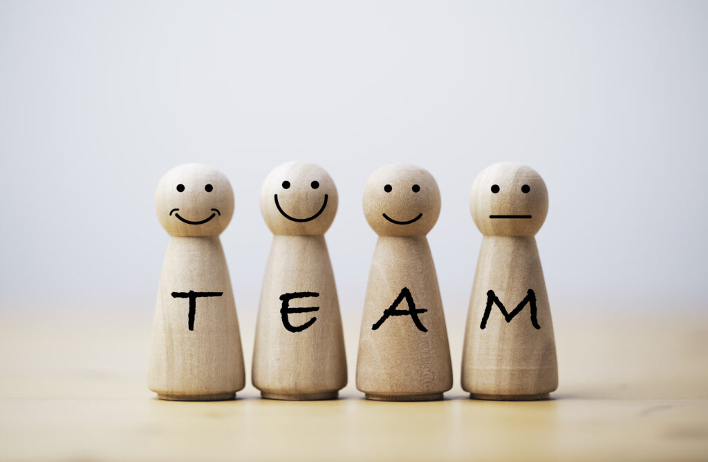 wooden figures smile face with team wording on body for teamwork